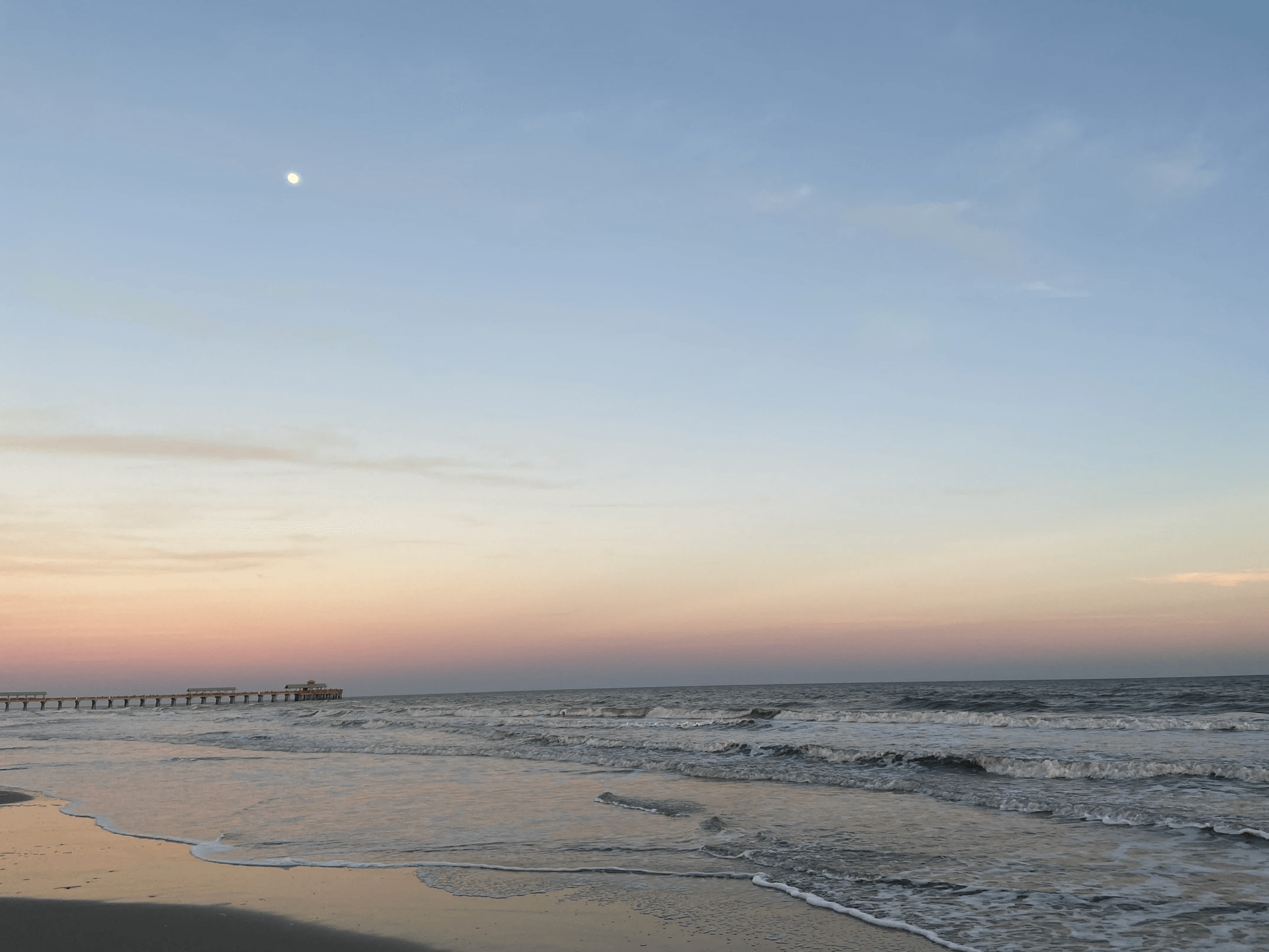beach with a pier on the background